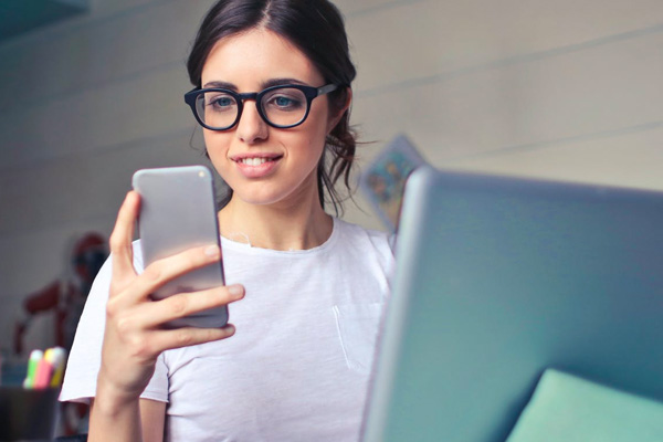 Girl with glasses smiling looking at her phone